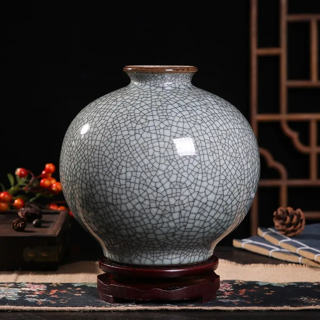 A rounded grey vase has a dense crackle pattern and a short, open neck