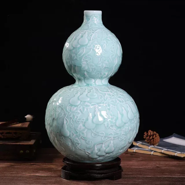 A pale green vase has a double-gourd silhouette and subtle surface decoration