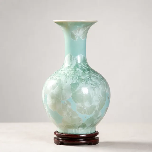 A pale blue-green vase has a rounded body, flared mouth and cloudlike crystalline pattern
