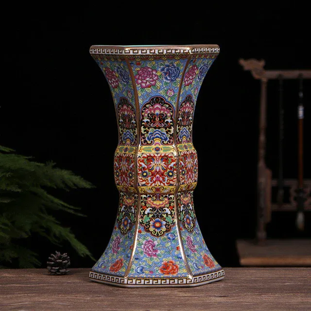 A faceted vase has a narrow waist, flared ends and closely arranged floral decoration