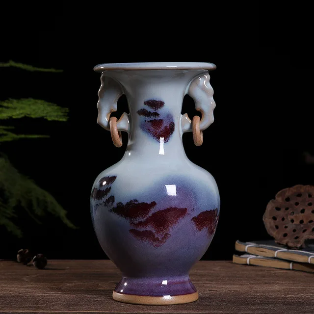 The pictured vase has purple and cream glaze with elephant-shaped handles at the neck