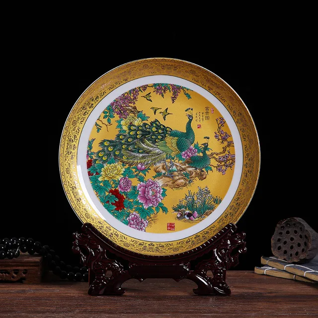The pictured display plate shows peacocks and flowers within a wide gold-tone border