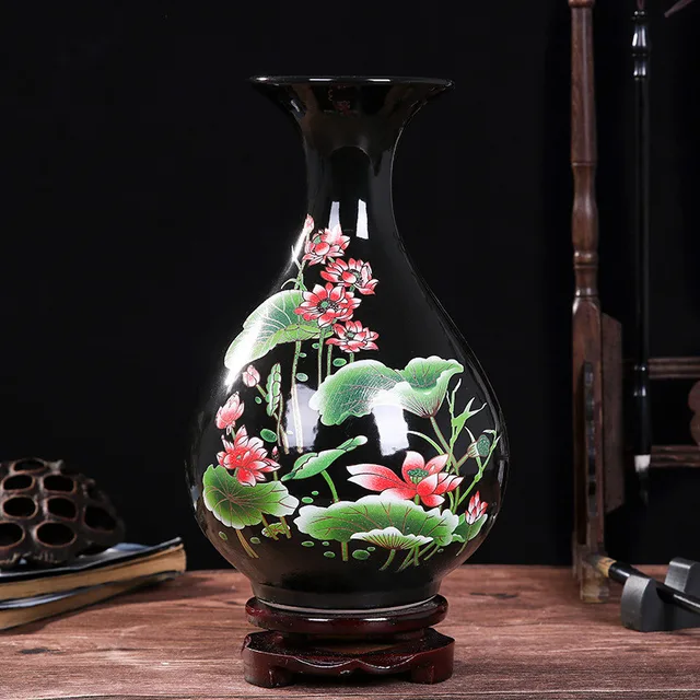 Pink lotus flowers and green leaves stand out against the black ground of the pictured vase