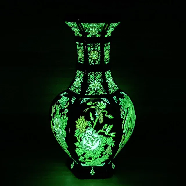 The pictured hexagonal vase displays green floral and bird decoration against a dark background