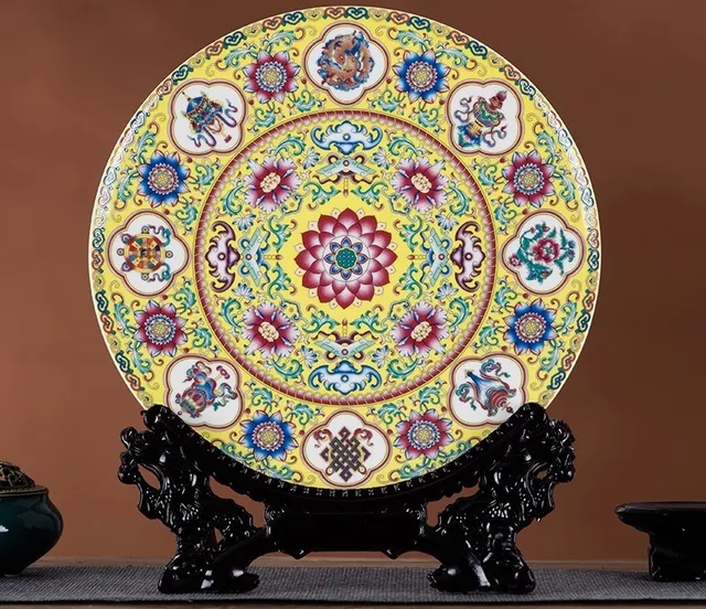 A round yellow display plate has a central lotus surrounded by auspicious-symbol medallions