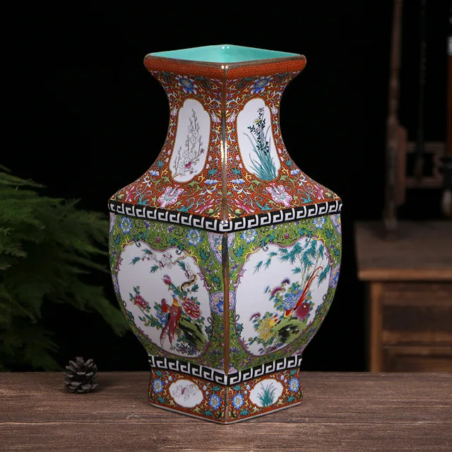 An angular vase has white floral and bird panels set within red and green patterned borders