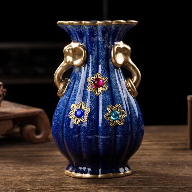 The pictured blue vase has gold-tone handles and small multicolor floral ornaments on its body