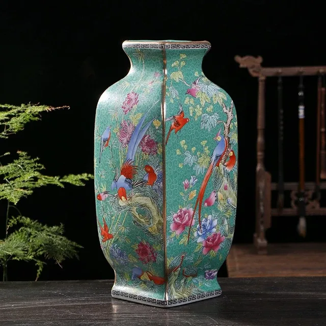 A faceted green-ground vase carries flowering branches and colorful bird details across its broad body