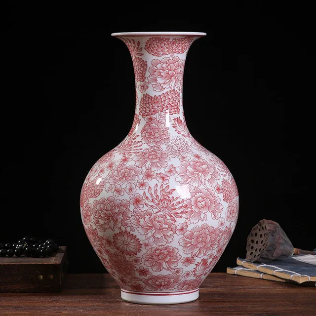 A rounded vase carries a fine red-and-white floral pattern from its body to its flared neck